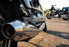 Aftermarket motorcycle exhaust system showing EPA compliance stamp with law enforcement vehicle in background