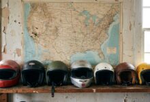 Various DOT-certified motorcycle helmets arranged on shelf with United States map background