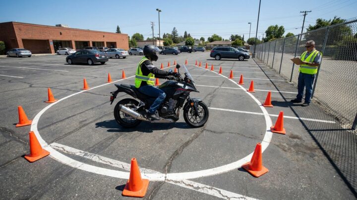 Motorcyclist executing U-turn during road test while examiner observes with scoring clipboard