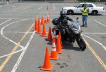 Motorcycle endorsement candidate executing cone weave during DMV road test evaluation